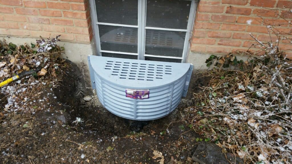 Window well with its cover installed against a brick foundation