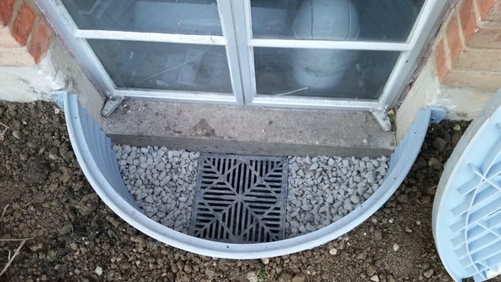 New window well with a drain grate set in clean gravel