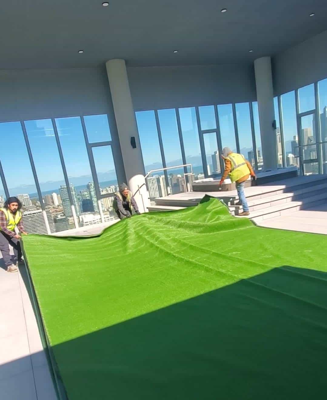 Streamline crew rolling out artificial turf on a high-rise terrace