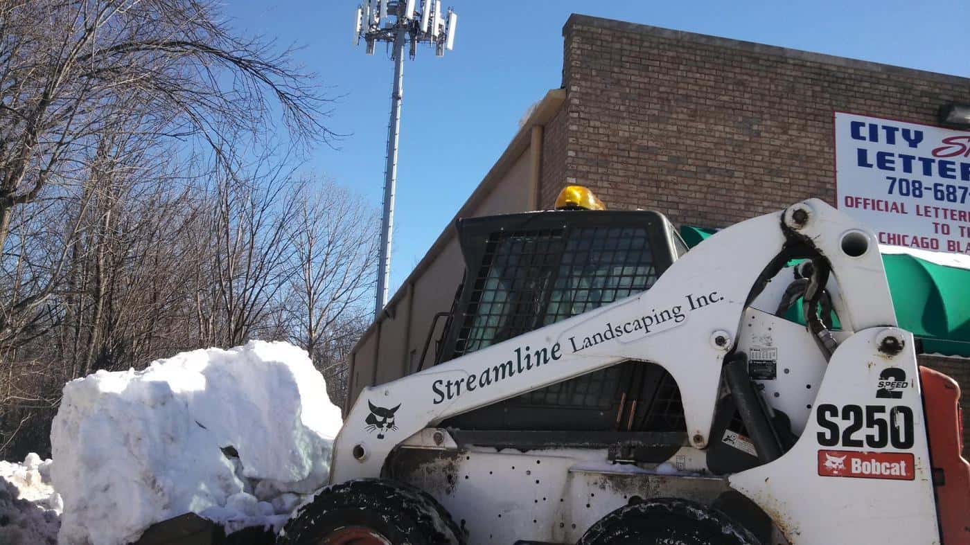 Streamline Landscaping skid steer moving large piles of snow