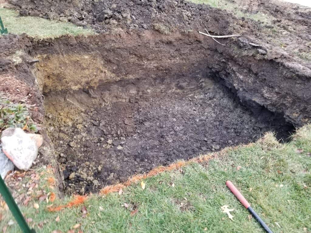 Pit dug in a lawn for an underground drainage chamber