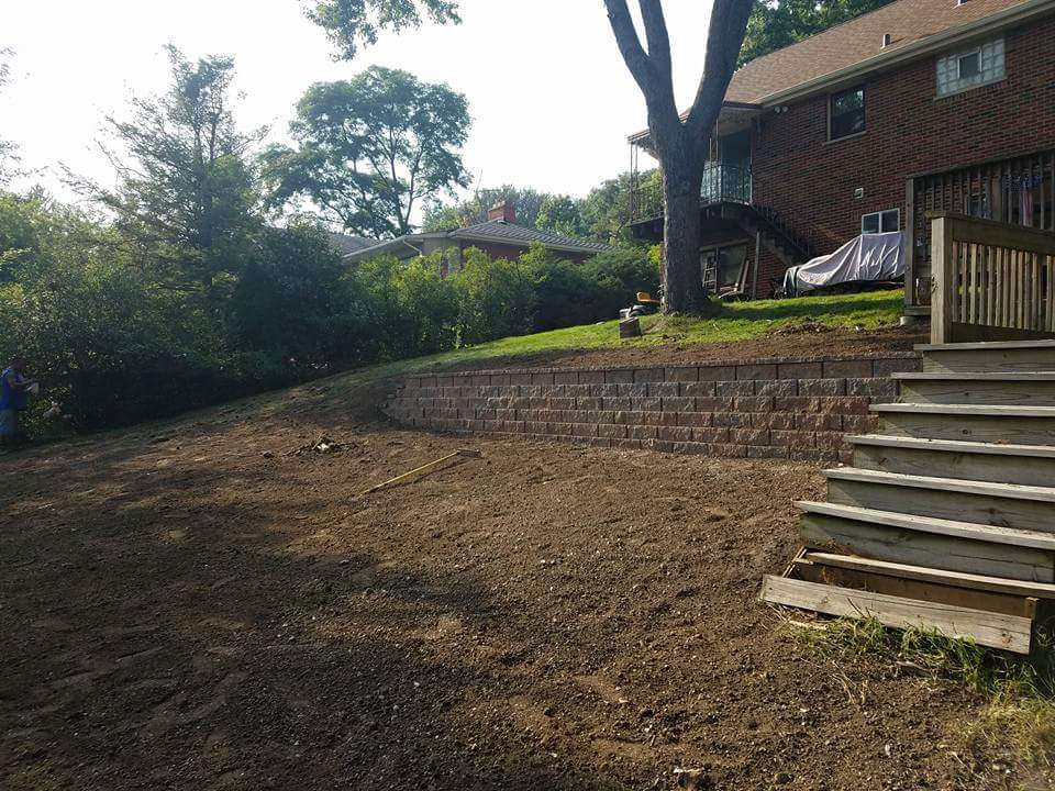 Block retaining wall with stone steps built into a regraded slope