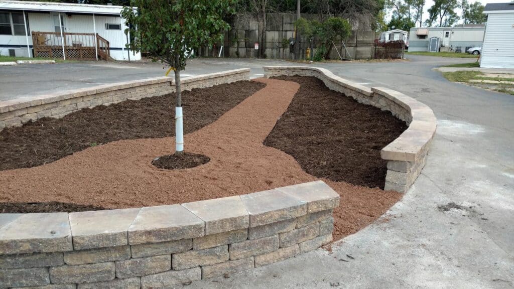 Curved block retaining wall planter with a new tree and crushed stone path