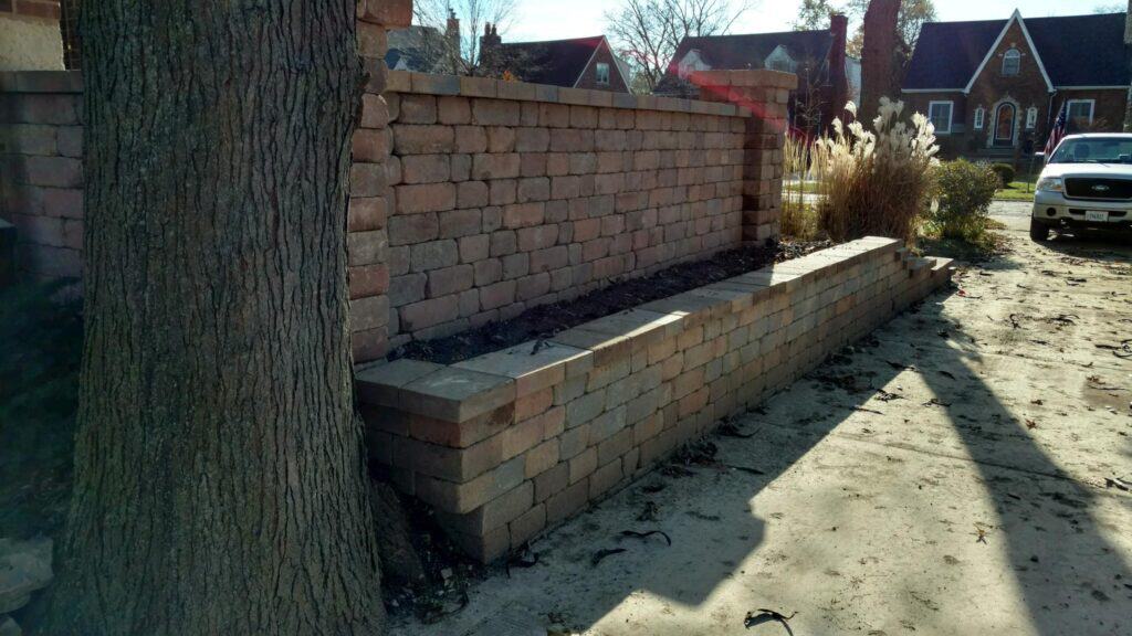 Rebuilt block retaining wall and planter along a driveway